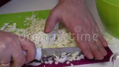 一个人做一份北京卷心菜沙拉。 用<strong>一把</strong>刀在切割板上磨碎卷心菜，然后把它扔进容器里。